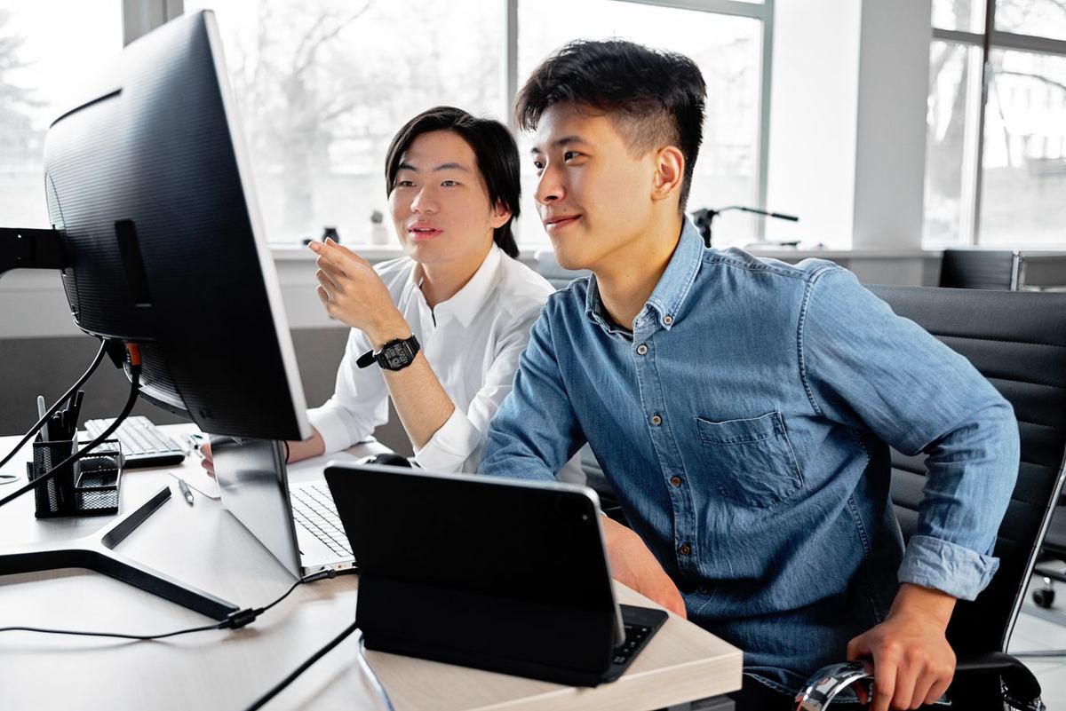 Two office staff looking at a monitor together, smiling